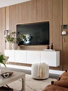 a living room with a large tv mounted on the wall and furniture in front of it