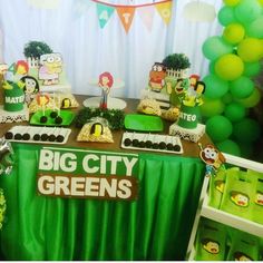 a table topped with lots of cakes and desserts covered in green frosted icing