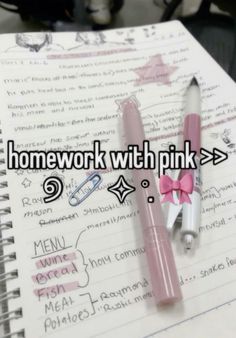 two pink pens sitting on top of a notebook next to an open notepad with writing