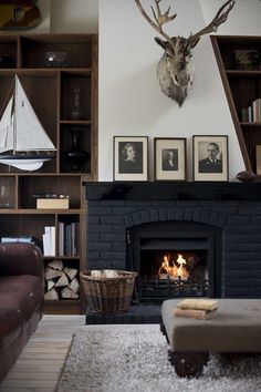 a living room filled with furniture and a fire place in front of a wall mounted deer head