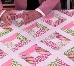 a woman is making a quilt with pink and green squares on the tablecloths