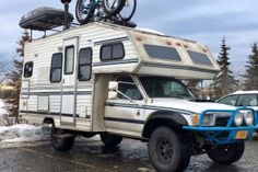 an rv parked in a parking lot with a bike on the top of it's roof