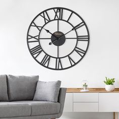 a living room with a couch, table and large clock on the wall above it