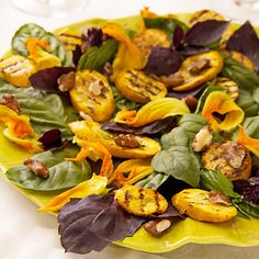 a green plate topped with lots of food on top of a white table covered in leaves