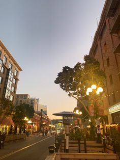 an empty city street at dusk with people walking on the sidewalk and shops in the background