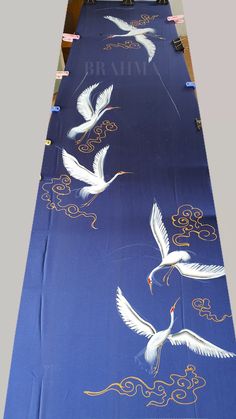 two white birds are flying over a blue table cloth with gold trimmings on it