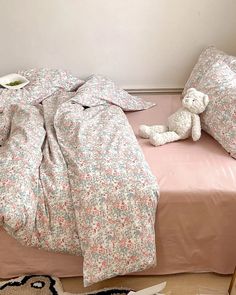 an unmade bed with two teddy bears on it and a pink comforter in the foreground