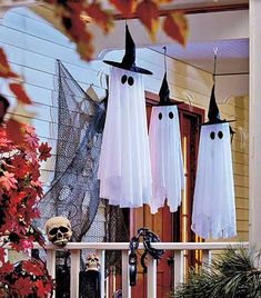 three halloween decorations hanging from the front porch with ghost faces and black hats on them