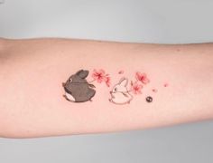 a small tattoo on the arm of a woman with flowers and a rabbit in it