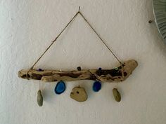 a piece of driftwood hanging from a wall with blue glass beads on the strings