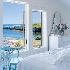 a bedroom with white walls and windows overlooking the ocean