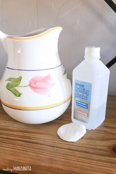 a white pitcher sitting on top of a wooden table next to a bottle of mouthwash