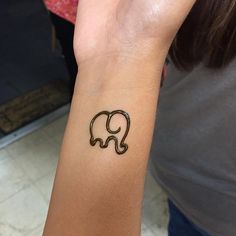 an elephant tattoo on the wrist of a woman