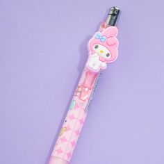 a pink hello kitty pen sitting on top of a purple surface