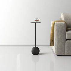 a small table with a cup on it next to a couch in a white room