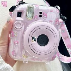 a person holding a pink camera with hello kitty on it's body and strap