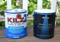 two cans of paint sitting on top of a wooden bench