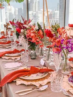 a table set with place settings and flowers in vases