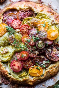 a pizza with tomatoes, cucumbers and other toppings sitting on top of a table