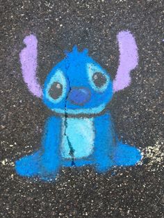 an image of a blue cartoon character painted on the ground with chalk pastel paint