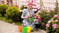 a woman sitting on the ground with buckets and cups in front of her,