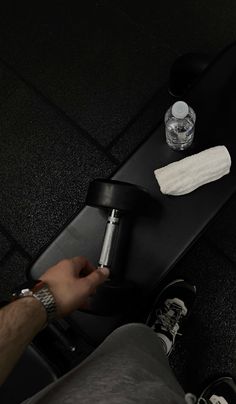 a person sitting on top of a skateboard next to a bottle of water and an object