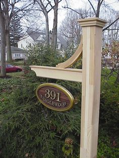 a sign that is on the side of a pole in front of some bushes and trees