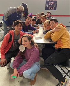 a group of young people sitting at a table posing for a photo in front of the camera