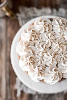 a white plate topped with a cake covered in frosting on top of a wooden table