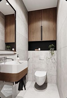 a bathroom with a toilet, sink and mirror next to it's tiled walls