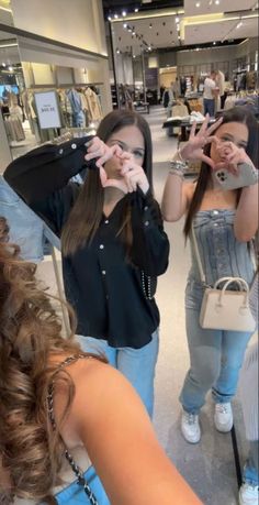 two young women standing in front of a mirror making the v sign with their hands