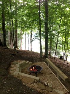 a fire pit in the middle of a wooded area with steps leading up to it