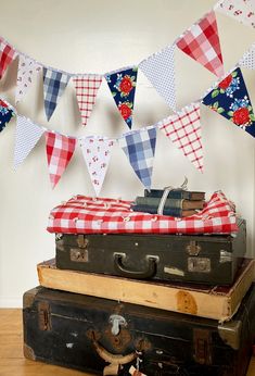 an old suitcase is sitting on top of some luggage and bunting flags are in the background