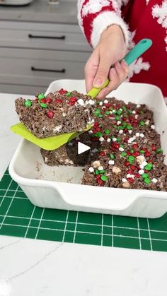 a person in a red and white sweater is cutting into a brownie with sprinkles