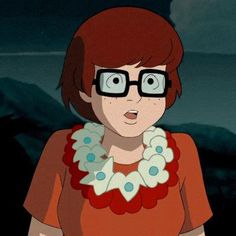 a woman wearing glasses and a necklace with flowers around her neck is staring at the camera