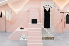 a room with pink walls and white steps leading up to the second floor, where there is a dress on display