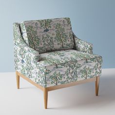 an upholstered chair sitting on top of a white floor next to a blue wall