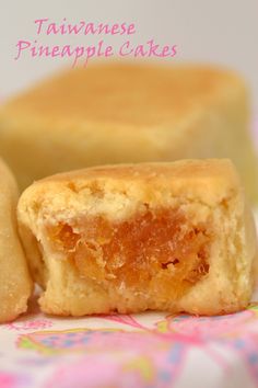 two pieces of pineapple cake sitting on top of a colorful table cloth with the words taiwan pineapple cakes