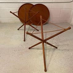 two wooden tables sitting next to each other on top of a cement floor in front of a white brick wall