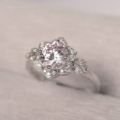 a white gold ring with a pink diamond surrounded by small diamonds on the side and in the center