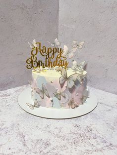 a birthday cake decorated with butterflies and the words happy birthday written on top is sitting on a table