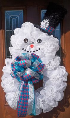 a snowman wreath is hanging on the front door with a blue and white bow