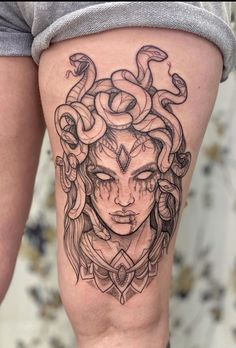 a woman's thigh with a tattoo design on her leg and snake around her head