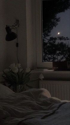 a bed sitting under a window next to a night sky filled with stars and moon