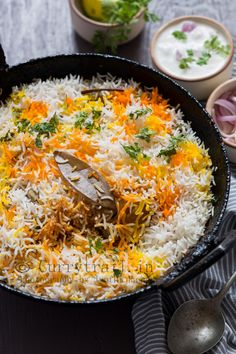 a pan filled with rice and vegetables on top of a table next to other dishes