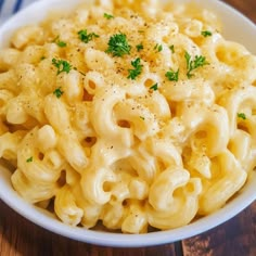 a white bowl filled with macaroni and cheese on top of a wooden table