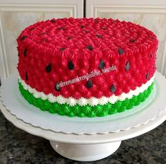 a watermelon cake with green and red icing on a white platter