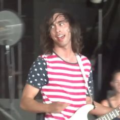 a man with long hair playing an electric guitar at a music festival in the dark