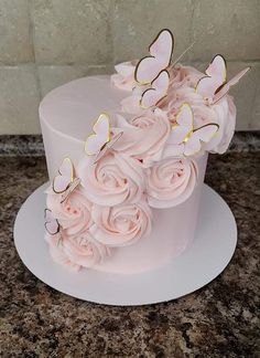 a white cake with pink flowers and butterflies on top