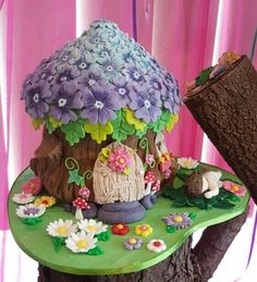 there is a cake that looks like a mushroom house on top of a tree stump